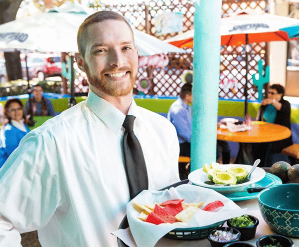 Server smiling with tray on restaurant patio